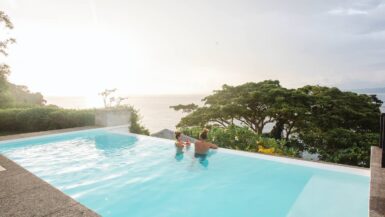 Couple relaxing in the infinity pool at Tavola Villa overlooking Savusavu Bay, Fiji